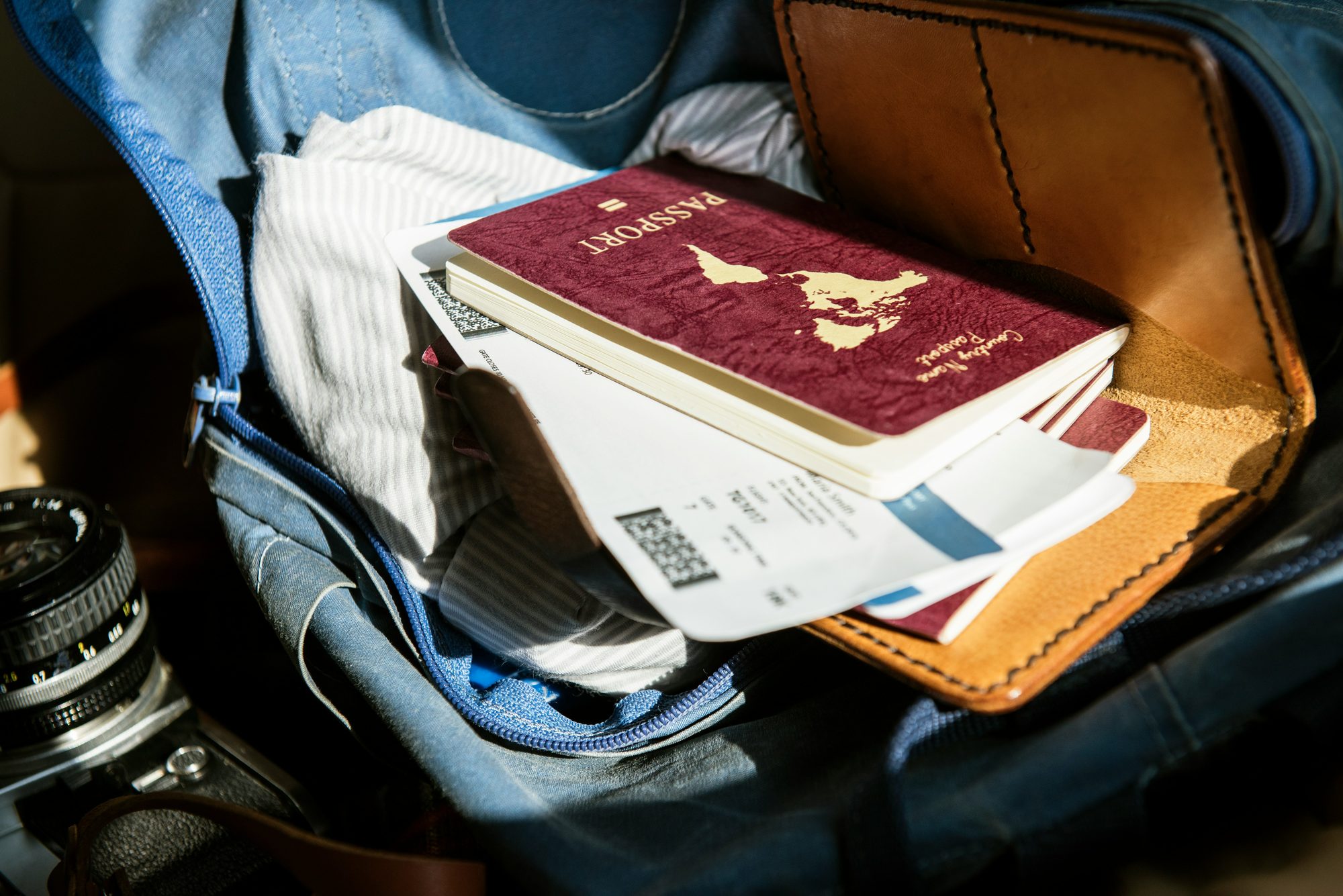 A packed travel bag with a passport and boarding pass resting on top