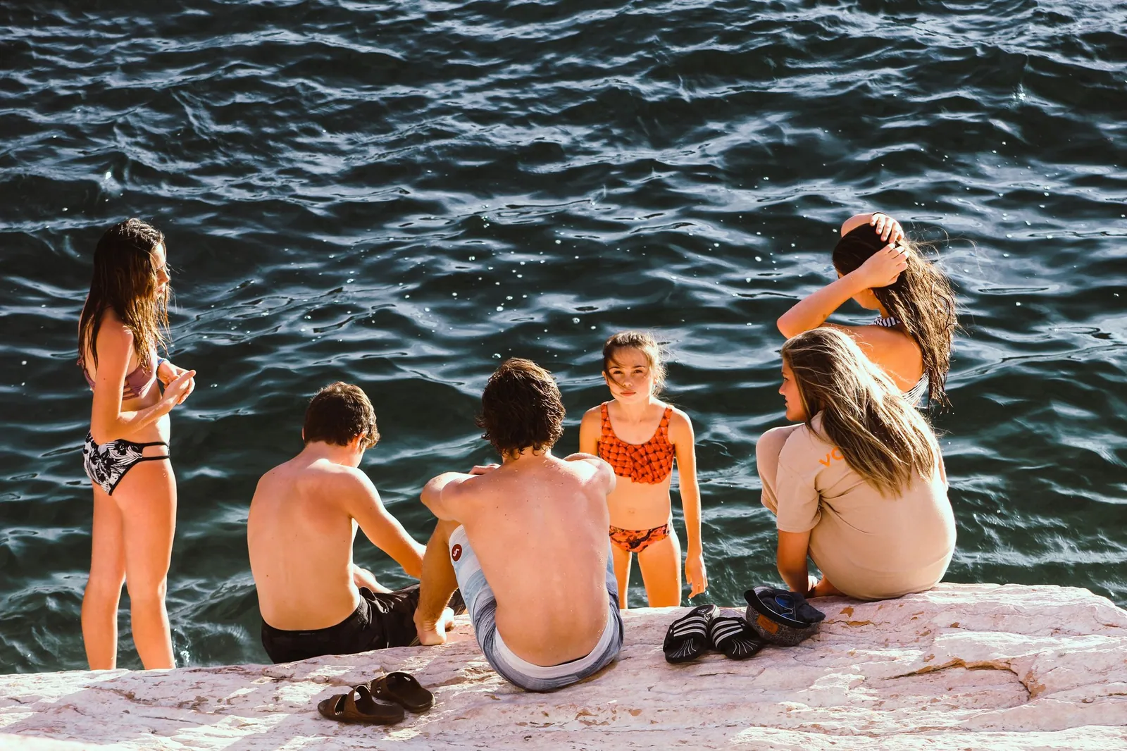A group of children sitting together at the water's edge on a summer afternoon