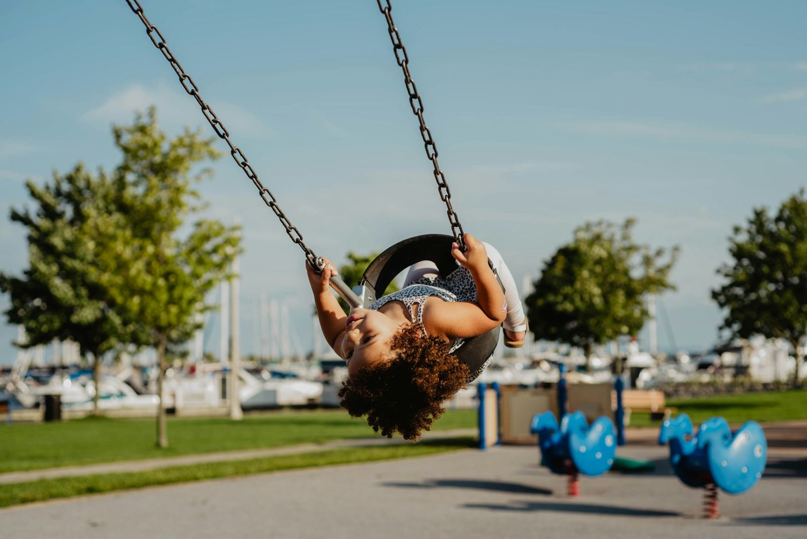 A child hanging upside down on a playground swing
