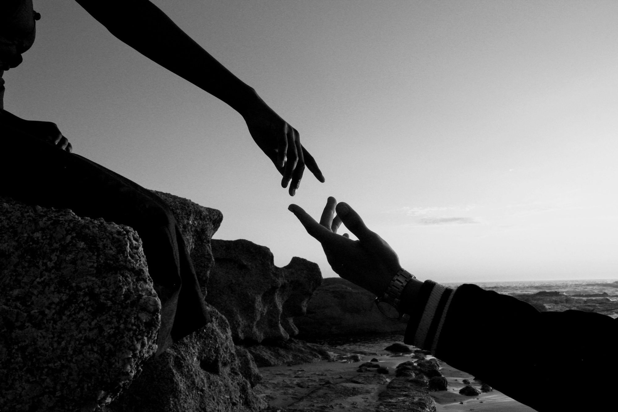 Two hands reaching toward one another across a gap in black and white