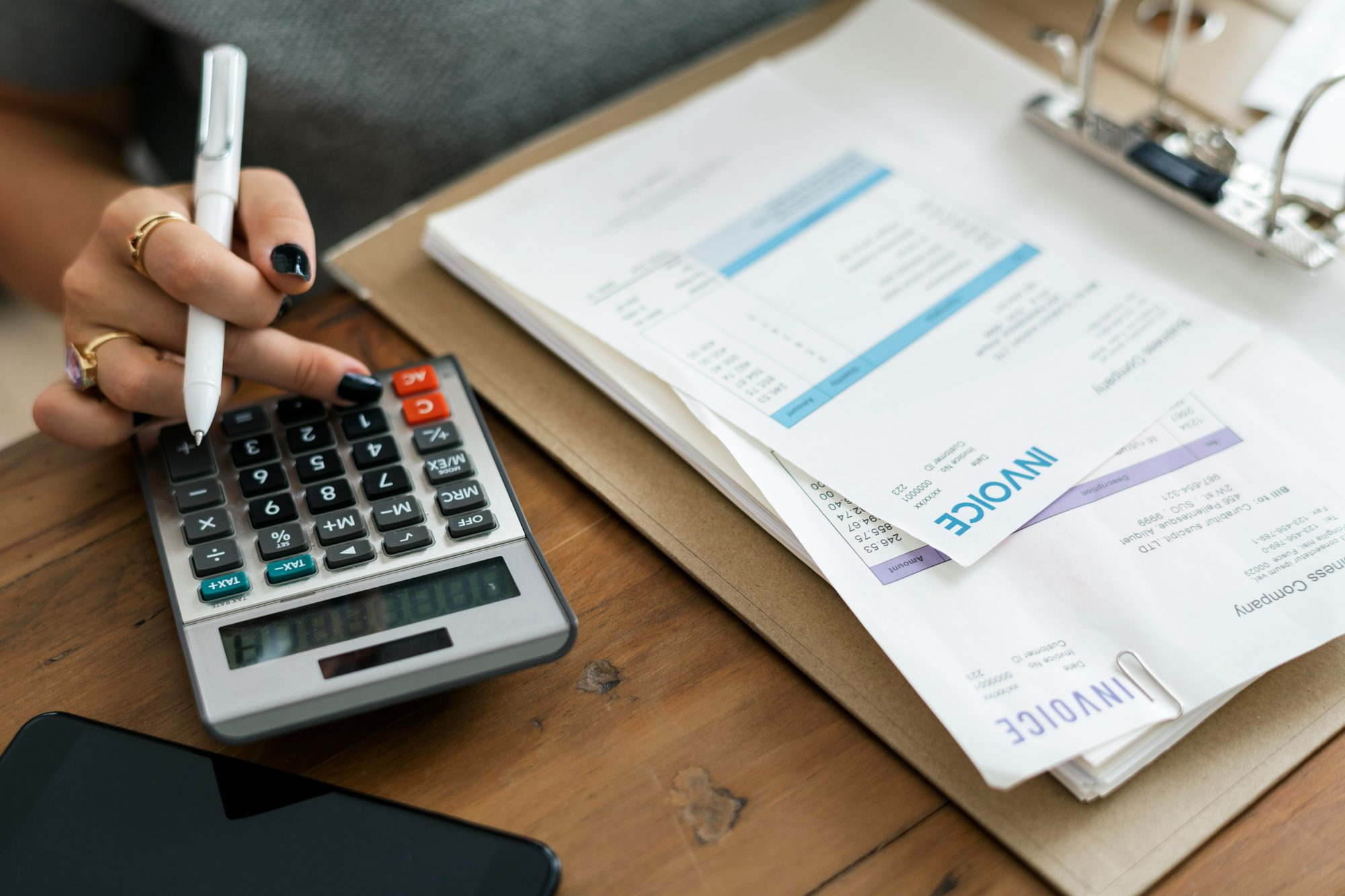 A young person working through a payslip with a calculator at a wooden desk