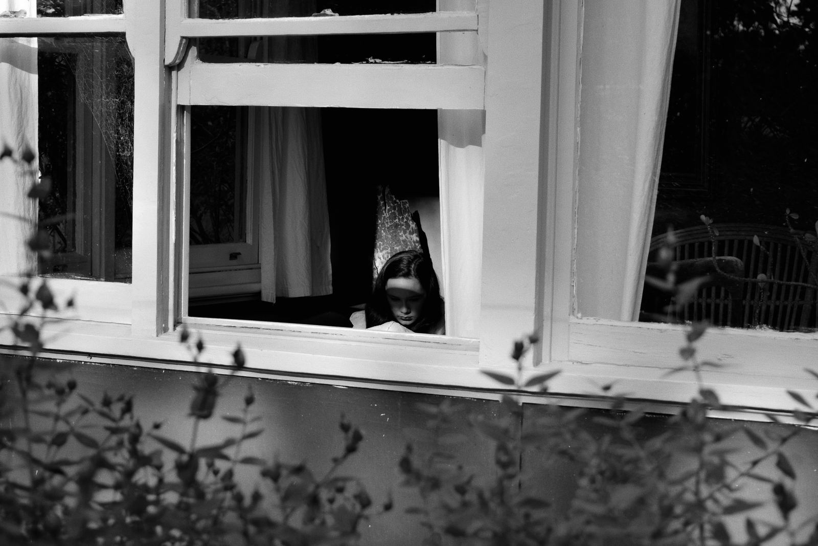 A child looking out of a window, waiting