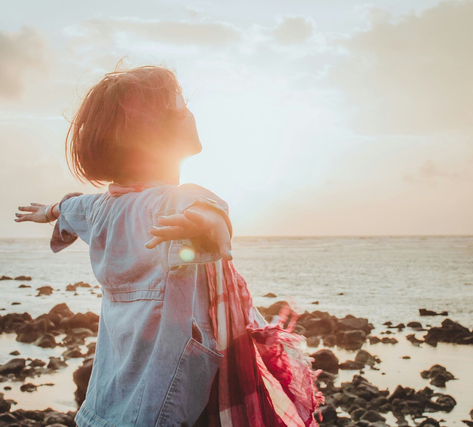 A girl standing with her arms open by the sea