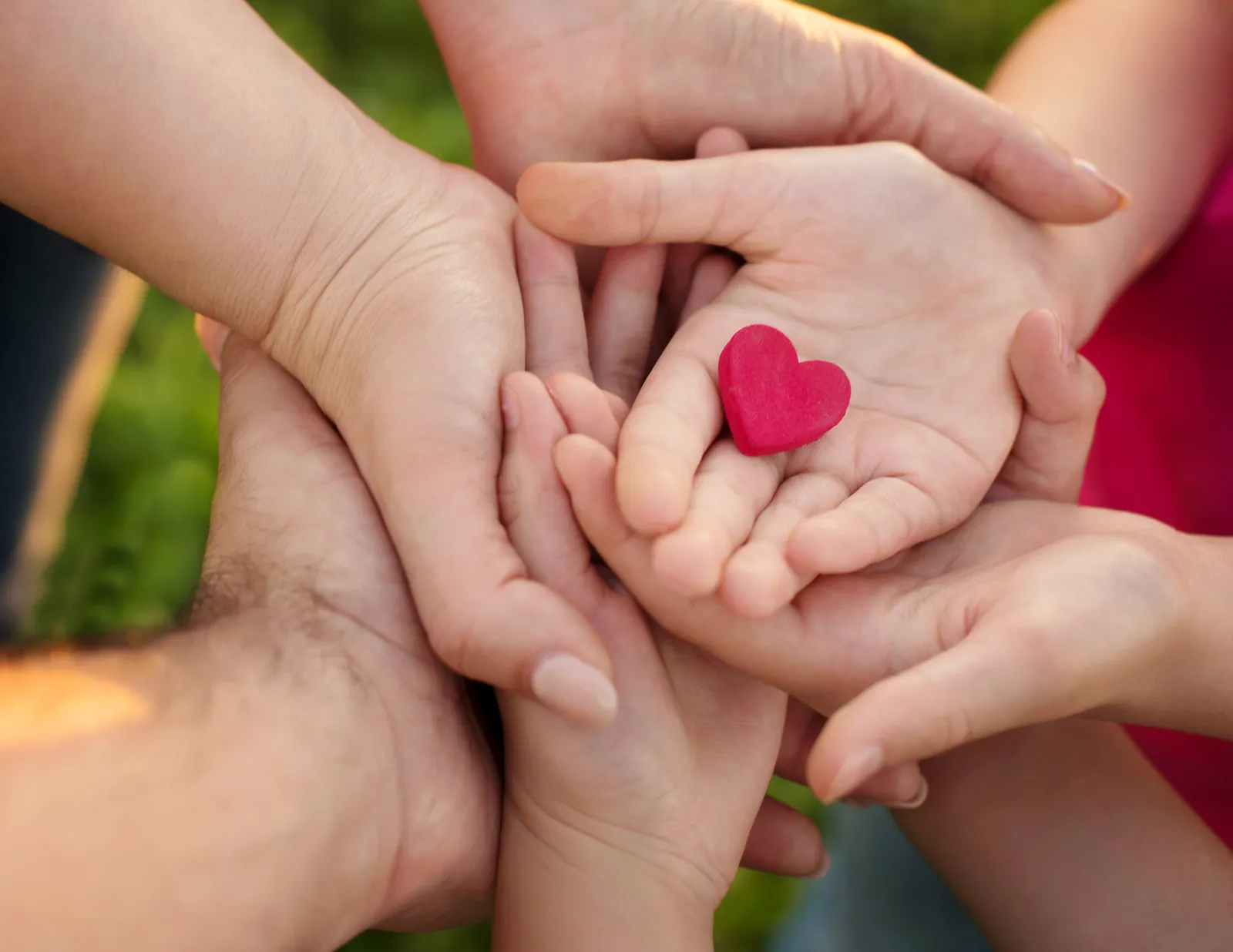 Adult and child hands gathered around a small red heart, representing connection before correction