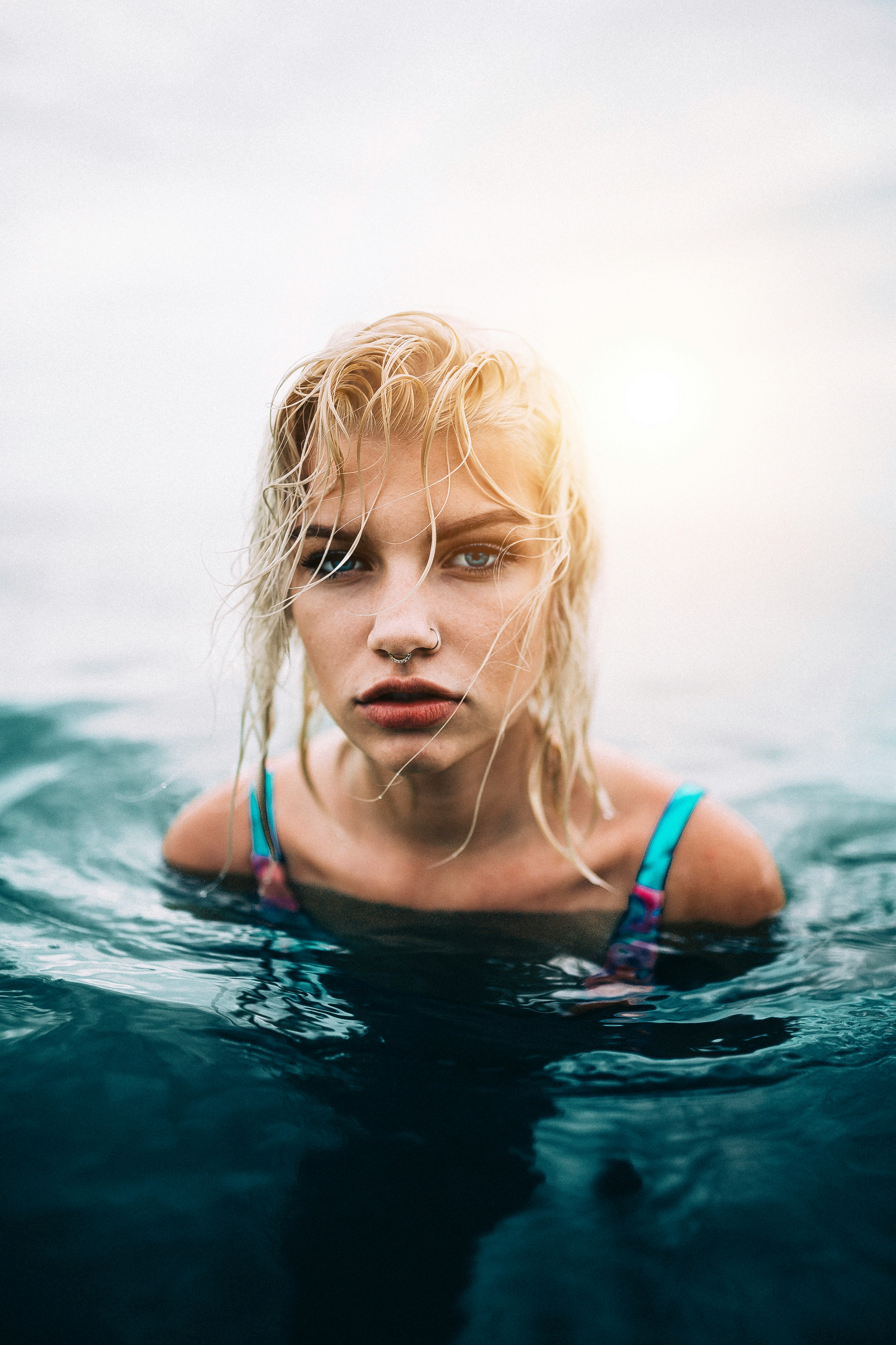A young person surfacing from open water into the light, catching their breath
