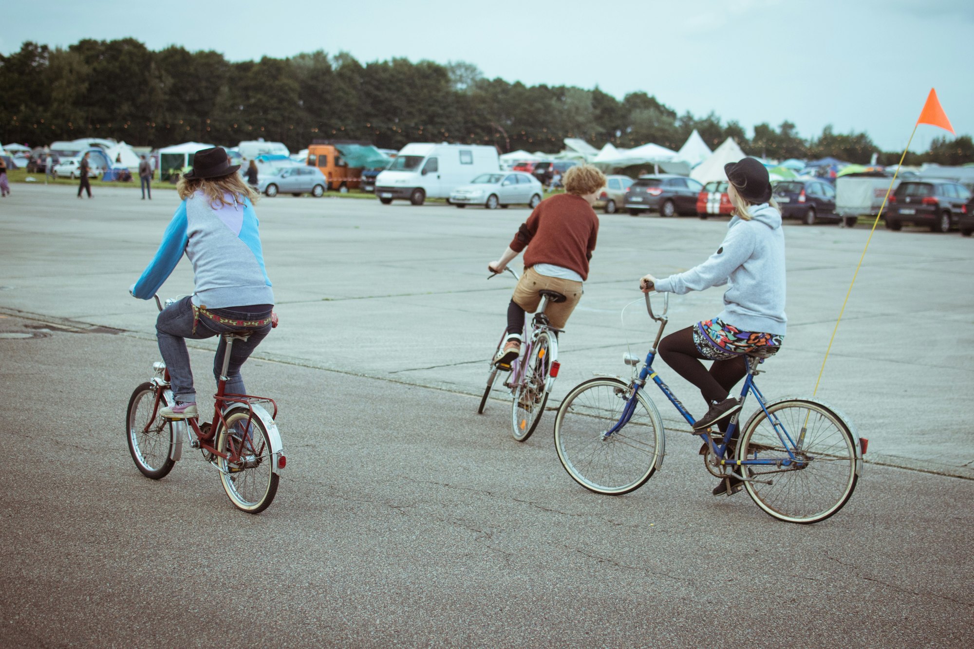 Three children cycling together across an open space