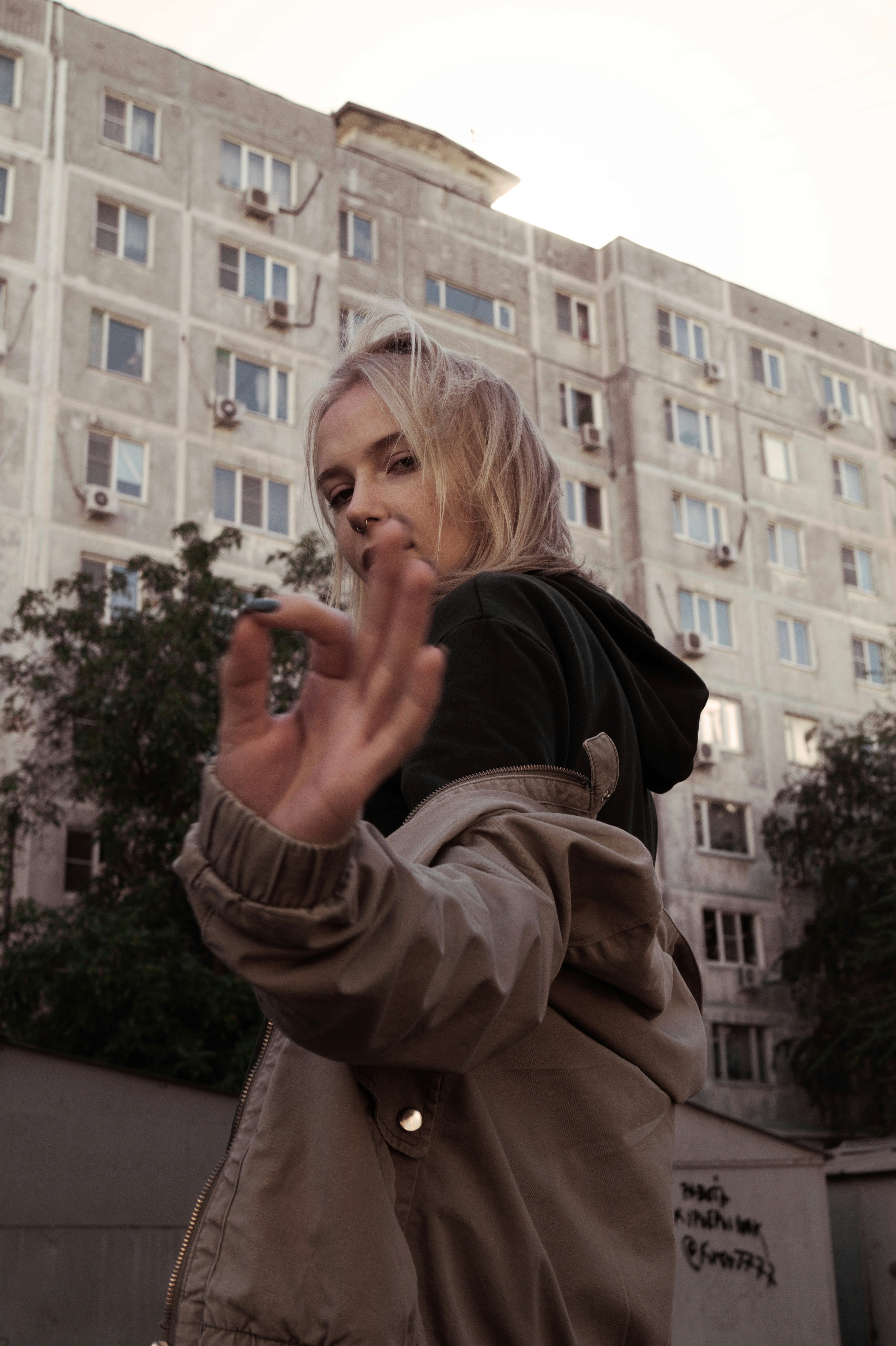 A teenage girl standing outside an apartment block, turning away from the camera