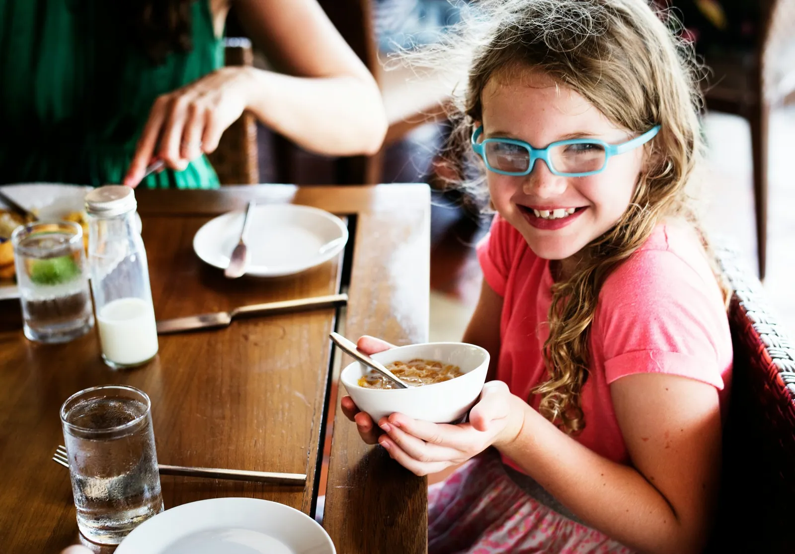 A child smiling over a bowl of cereal at a family table