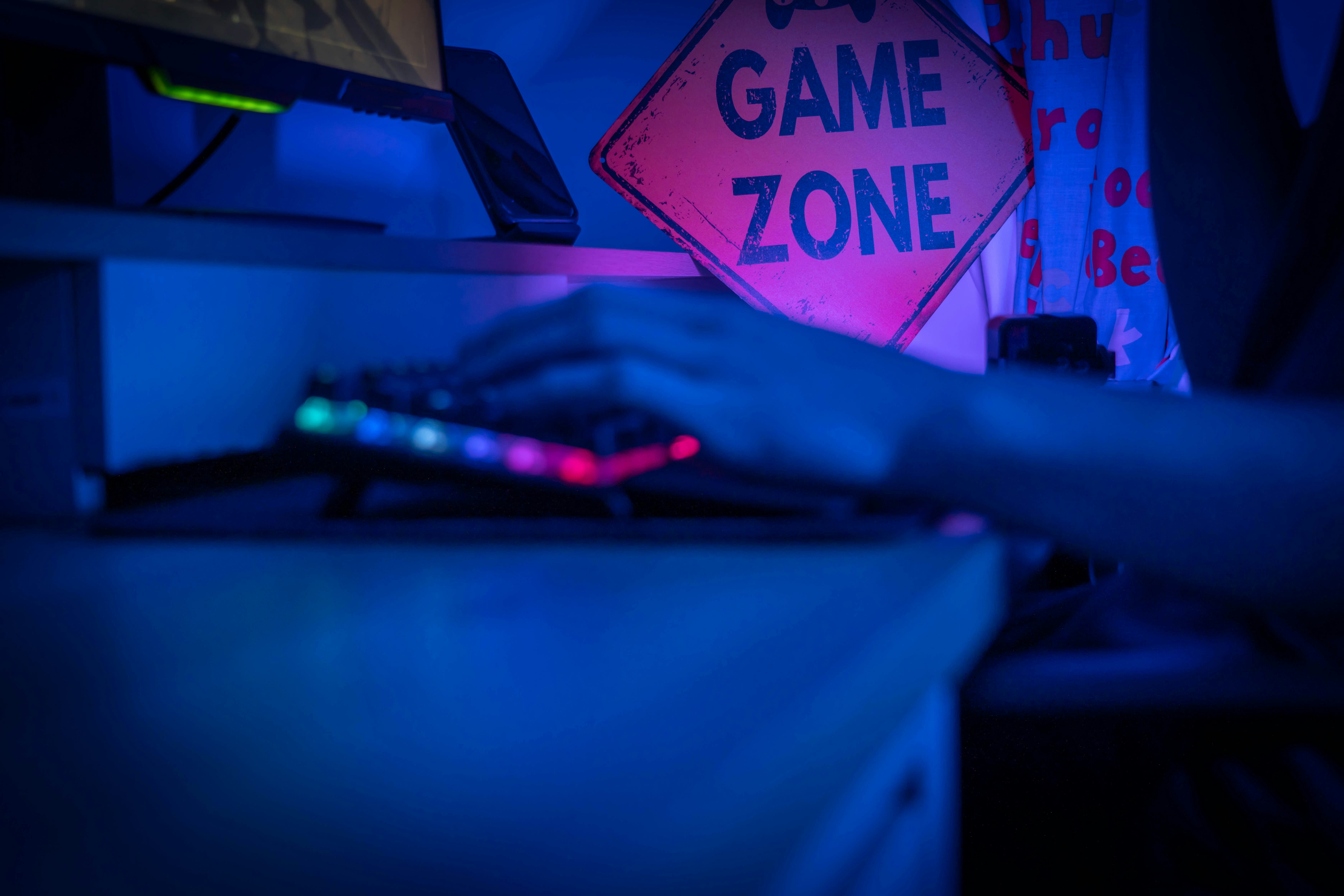 Hands on a backlit keyboard in front of screens washed in blue and pink light