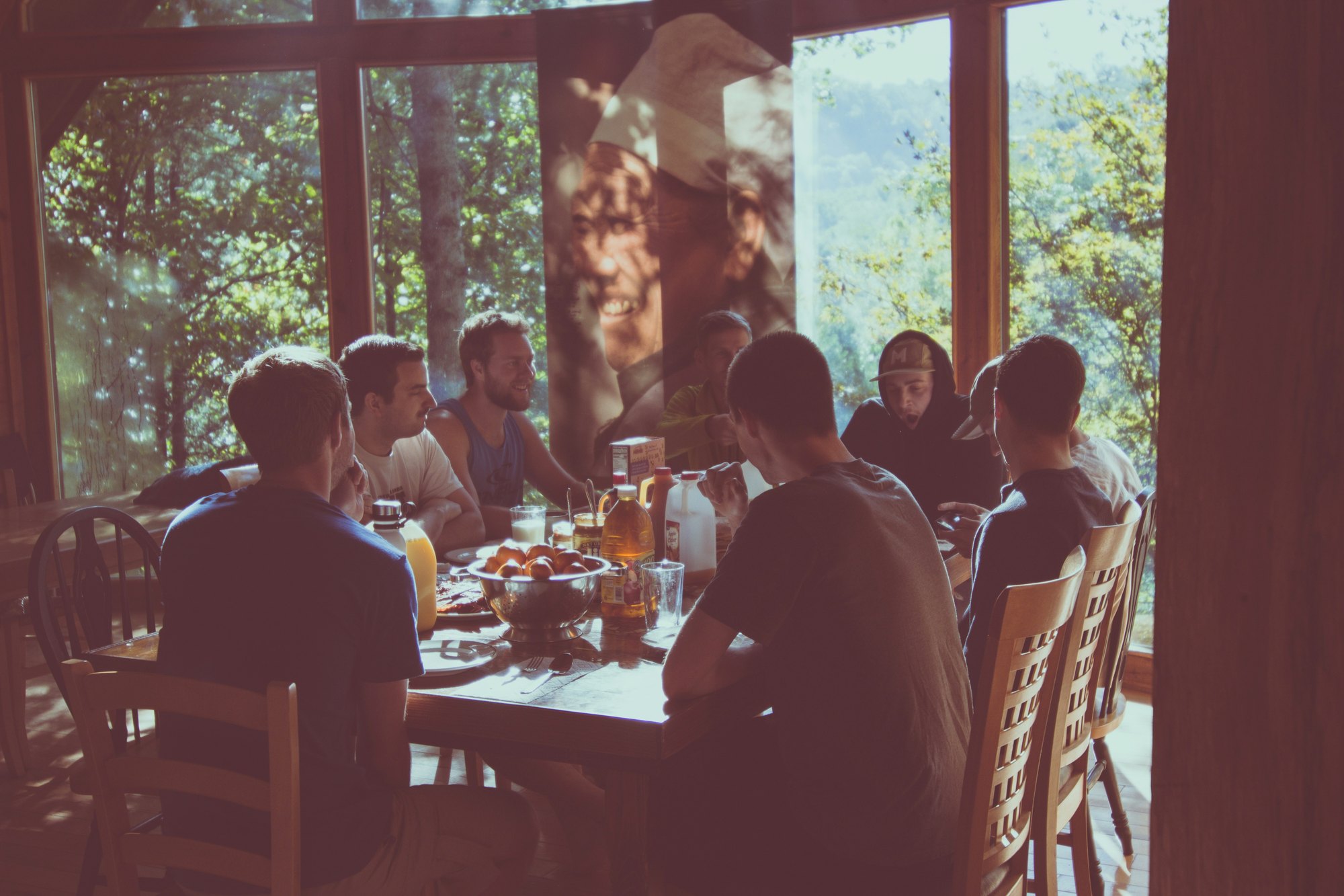 A family sitting around a long table together in a sunlit room