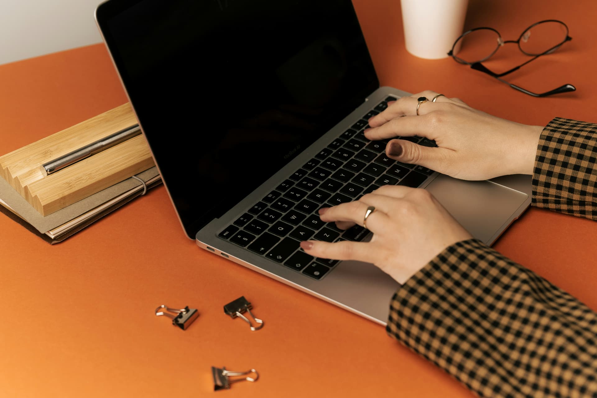 A warm-toned working desk with notebooks, glasses and a laptop.