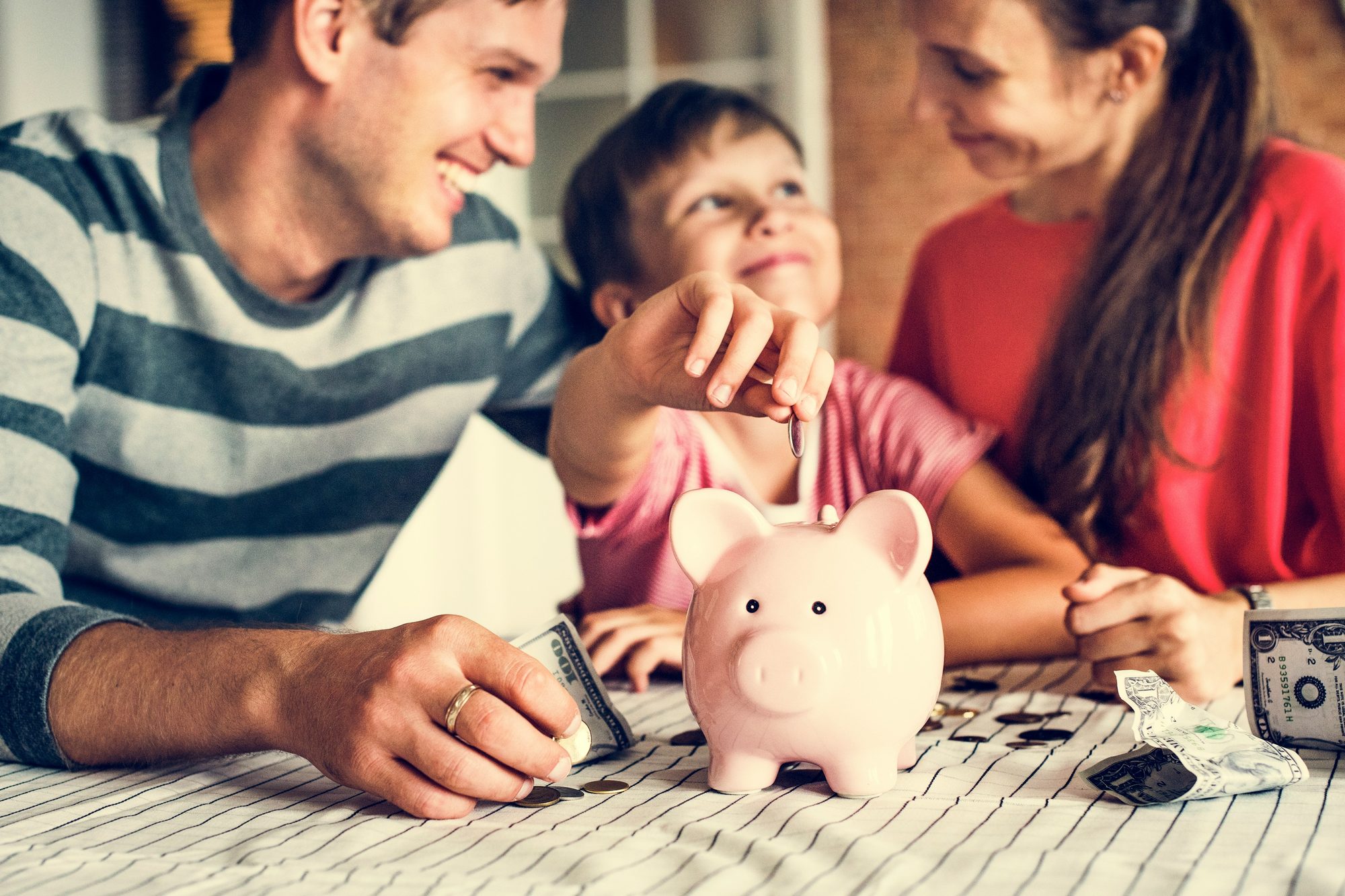 A family sitting together at a table putting coins into a piggy bank