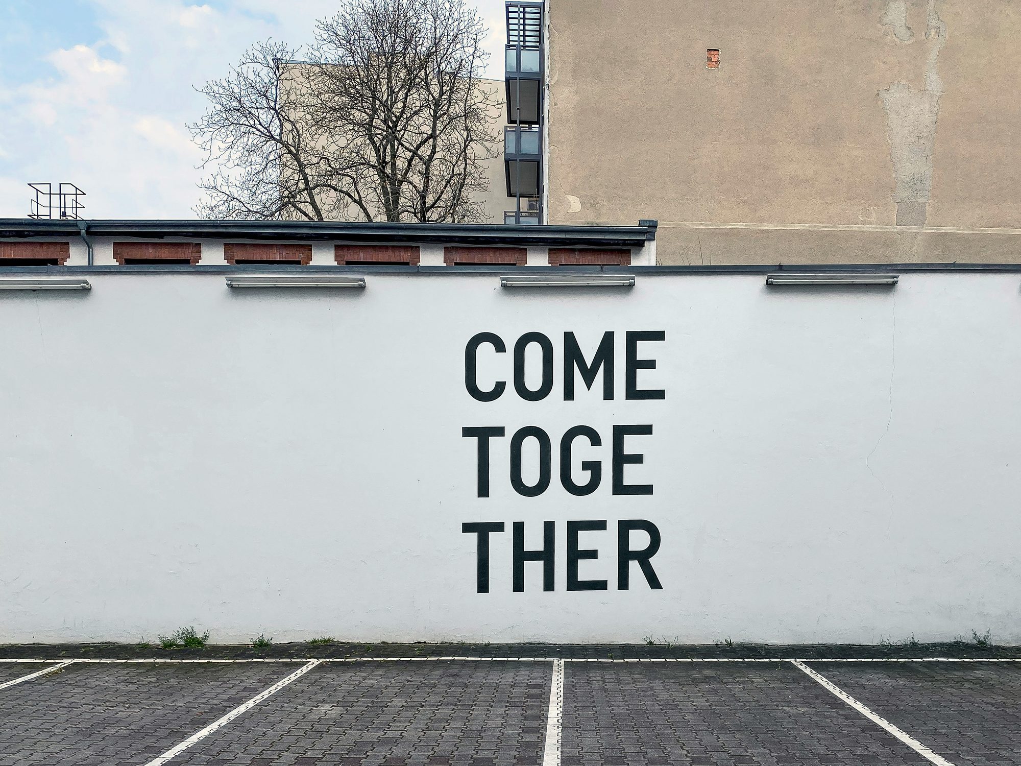 Large painted lettering on a white wall reading COME TOGETHER