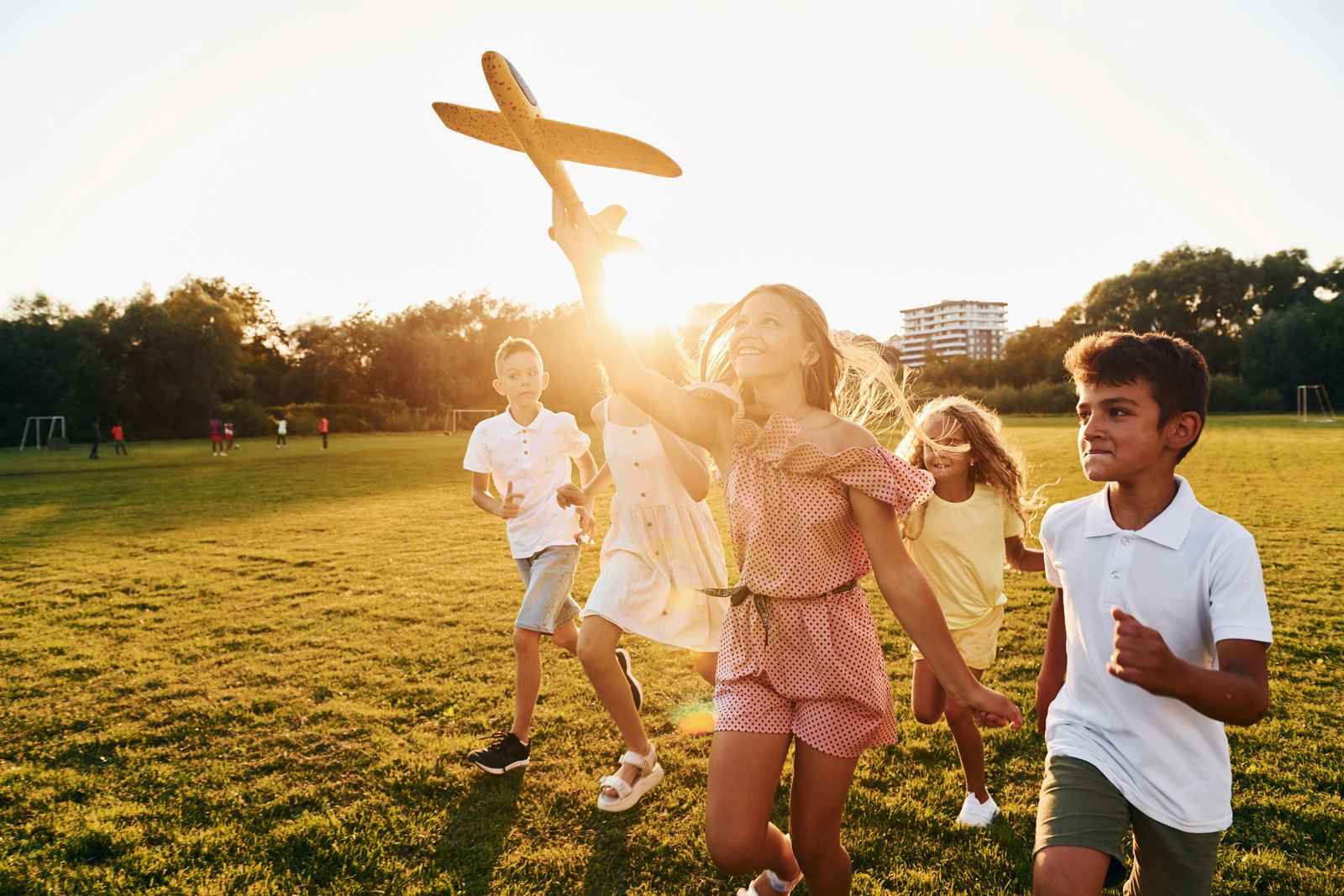 Children running across a field at sunset