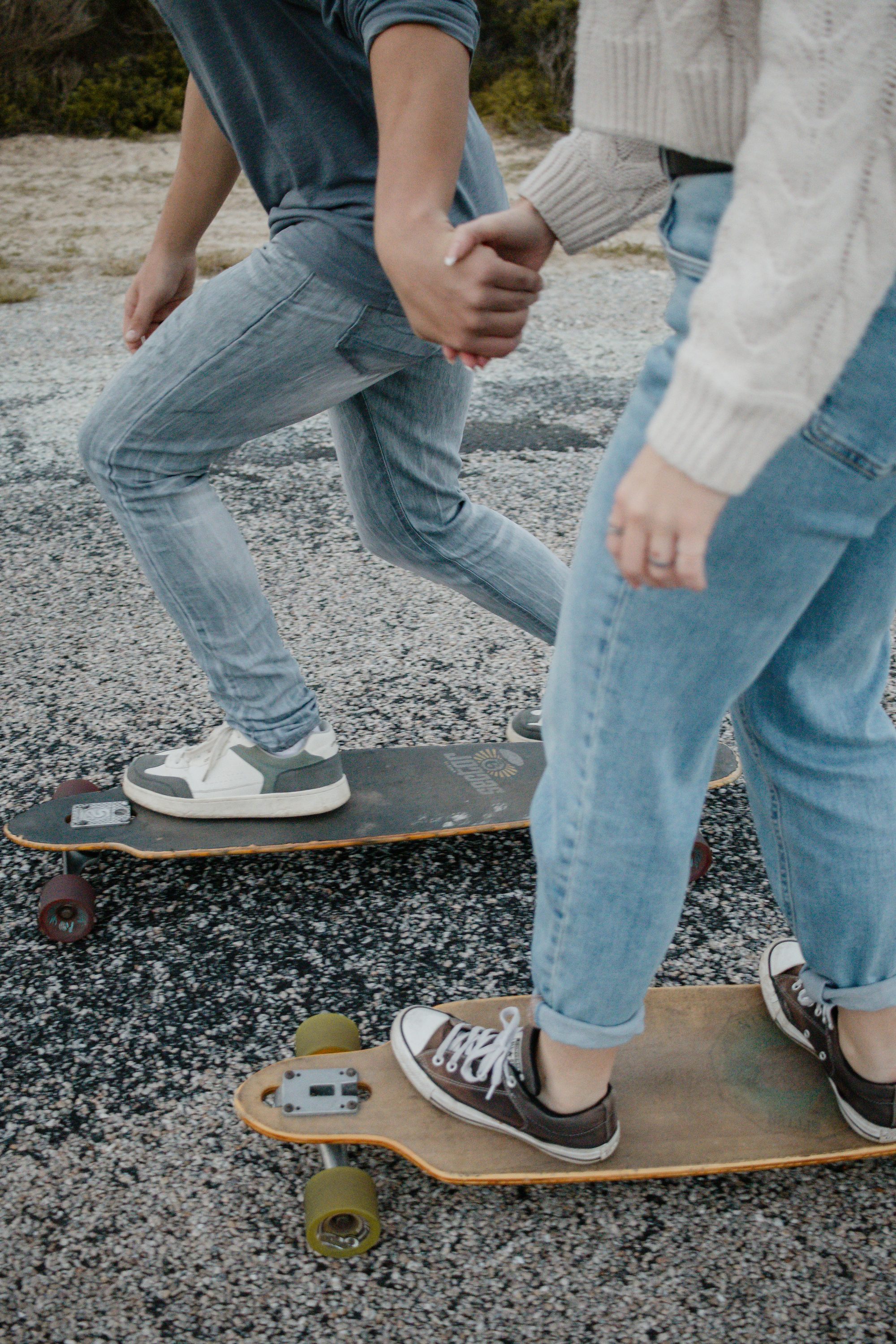 Two teenagers steadying each other while sharing a skateboard on a path