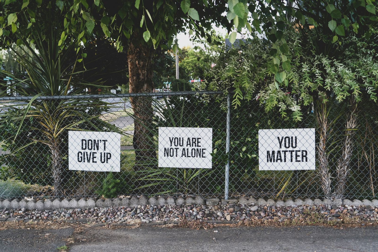 Signs on a fence reading do not give up, you are not alone, you matter