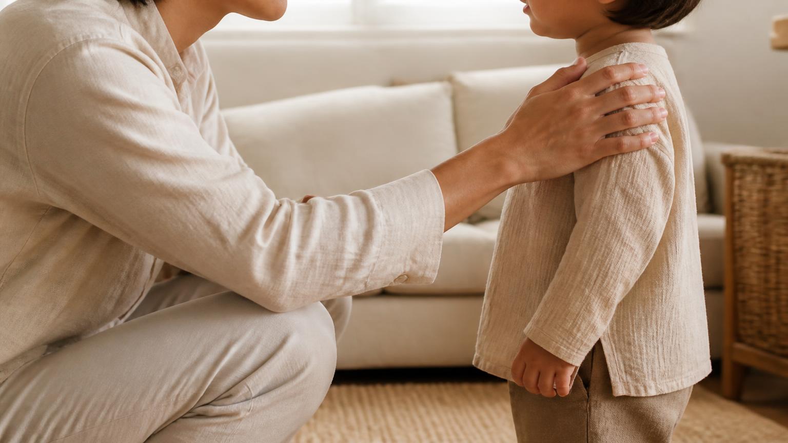 A parent kneeling at a child's eye level with a steady hand on their shoulder