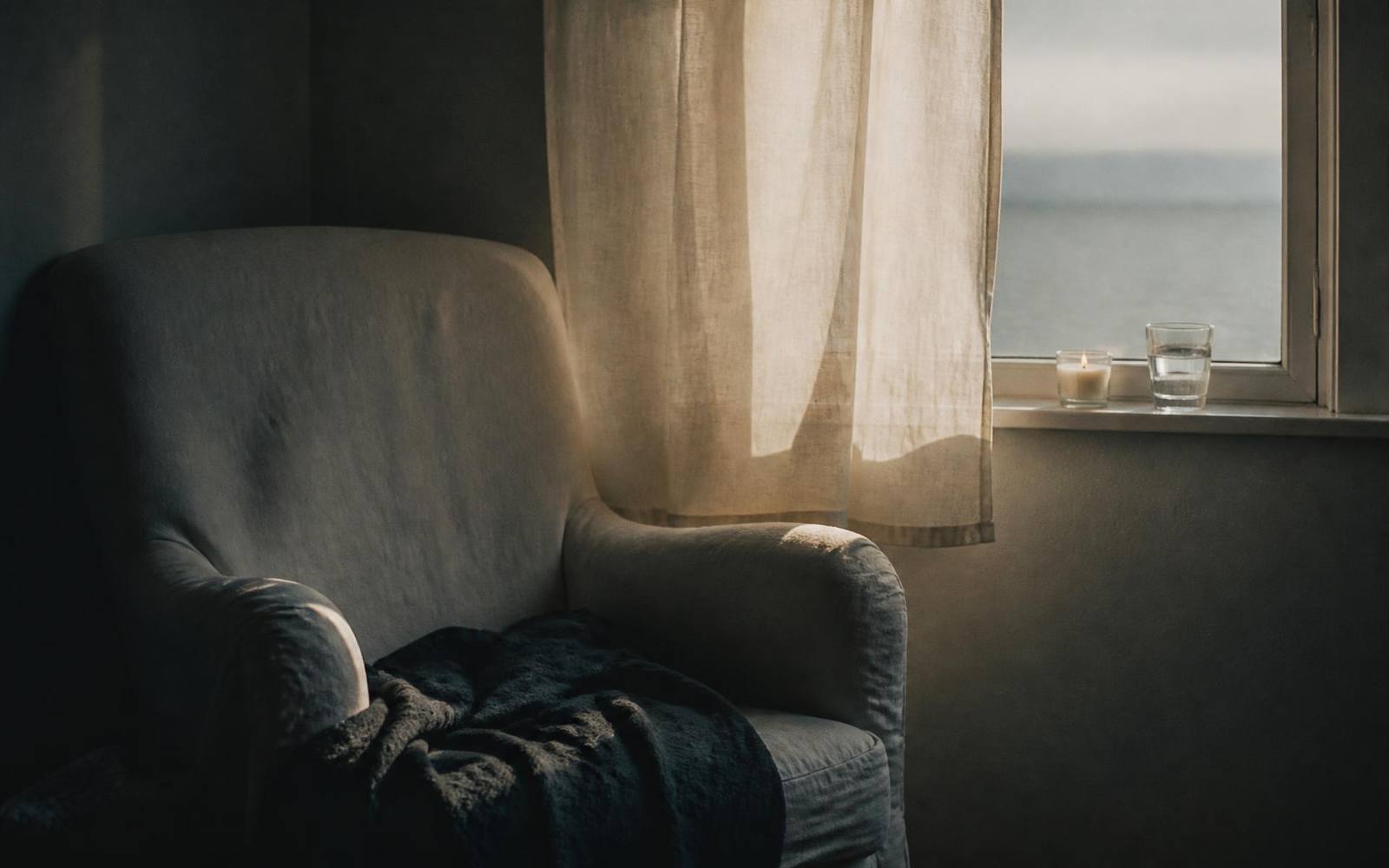 A quiet armchair beside a window with a candle