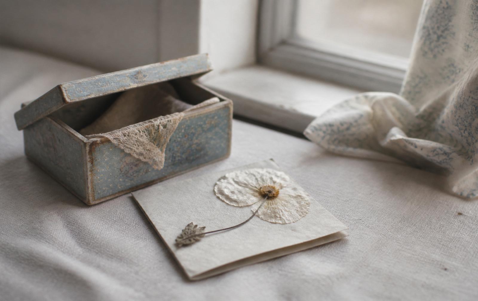A quiet child's bedroom corner with a folded blanket and a single pressed leaf on the windowsill